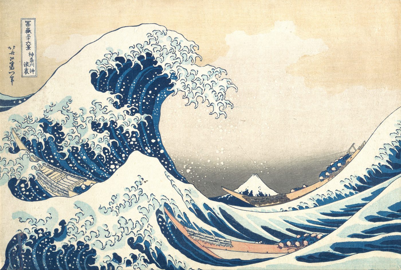 A woodblock print of a huge blue wave curling over three narrow boats of rowers, its crest breaking into claw-like spray, with small snow-capped Mount Fuji in the distance.